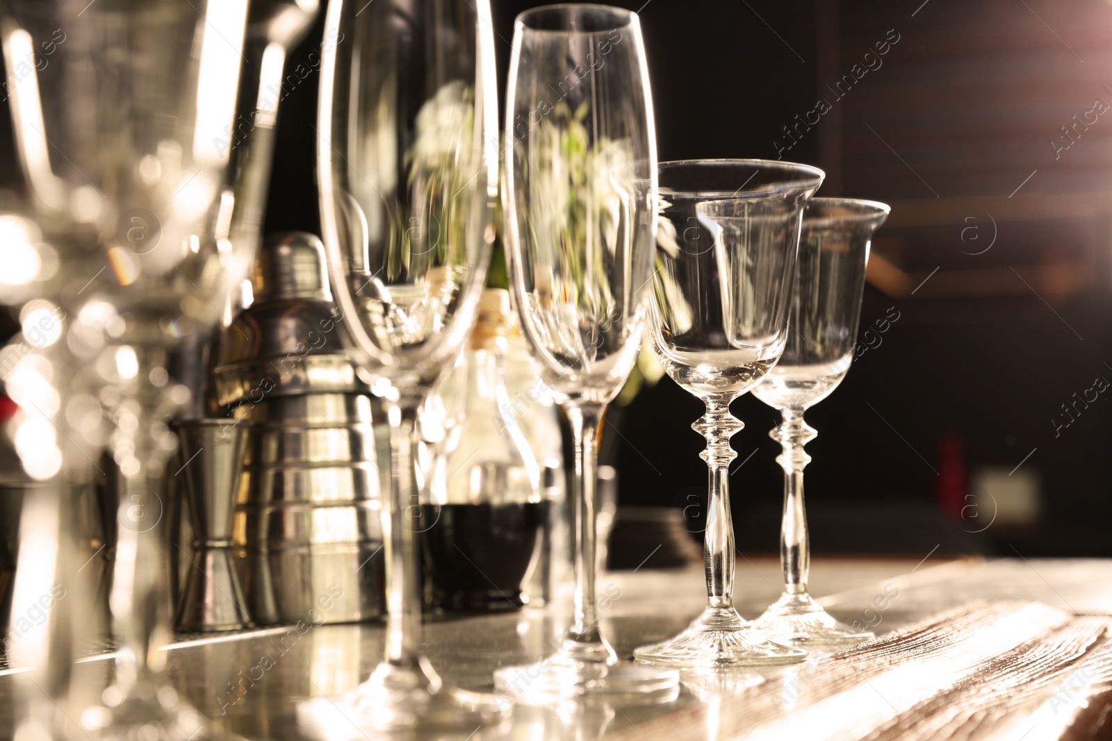 Photo of Different empty clean glasses on counter in bar, closeup