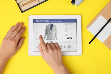 Photo of Woman with tablet shopping online on yellow background, top view