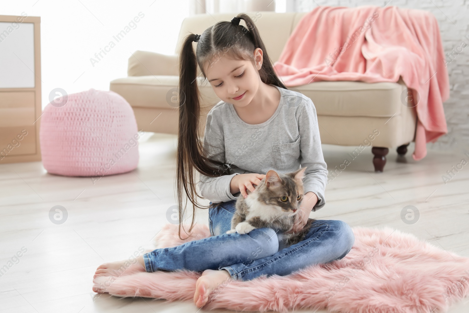 Photo of Cute little girl with cat sitting on floor at home