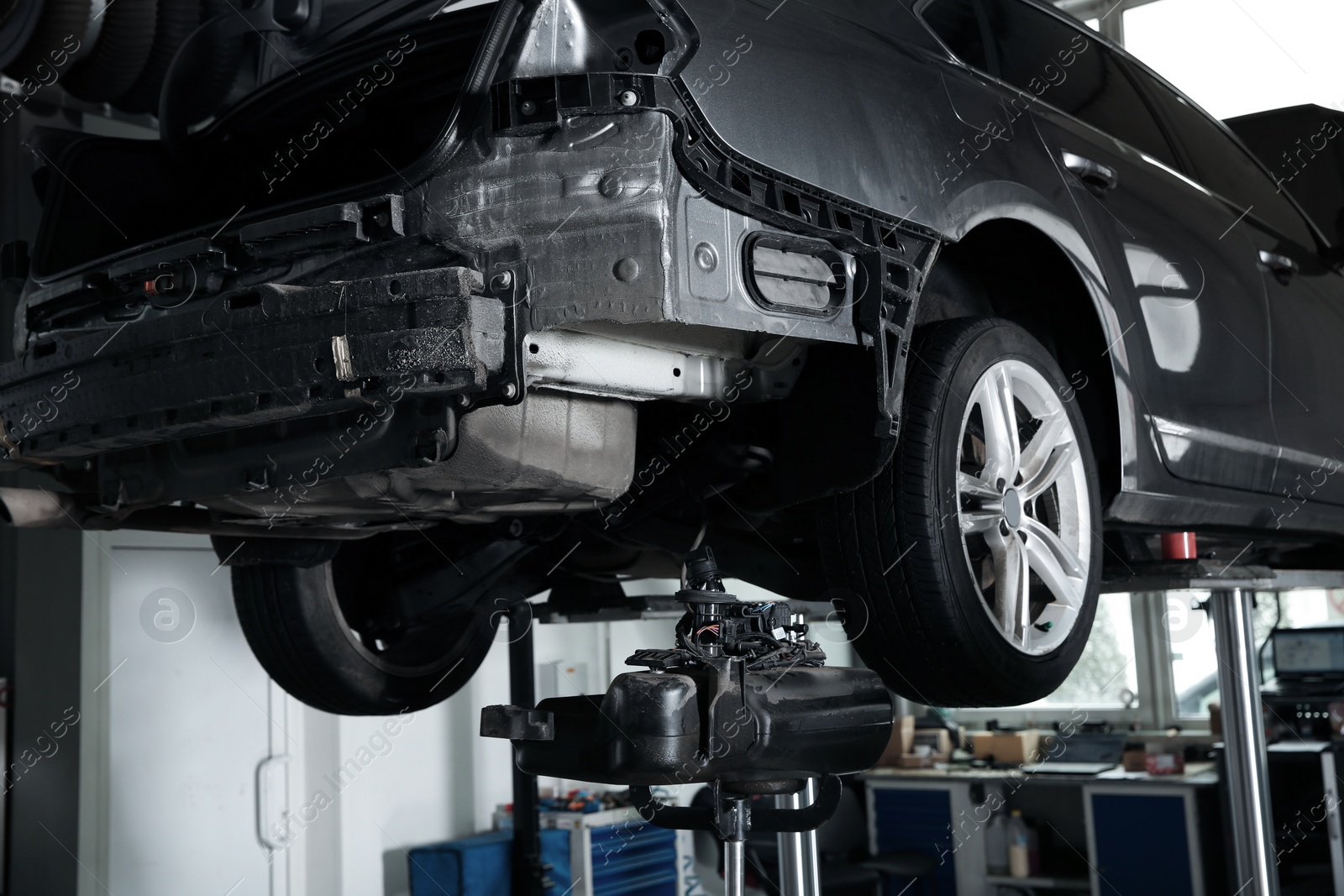 Photo of Modern car on hydraulic lift at automobile repair shop