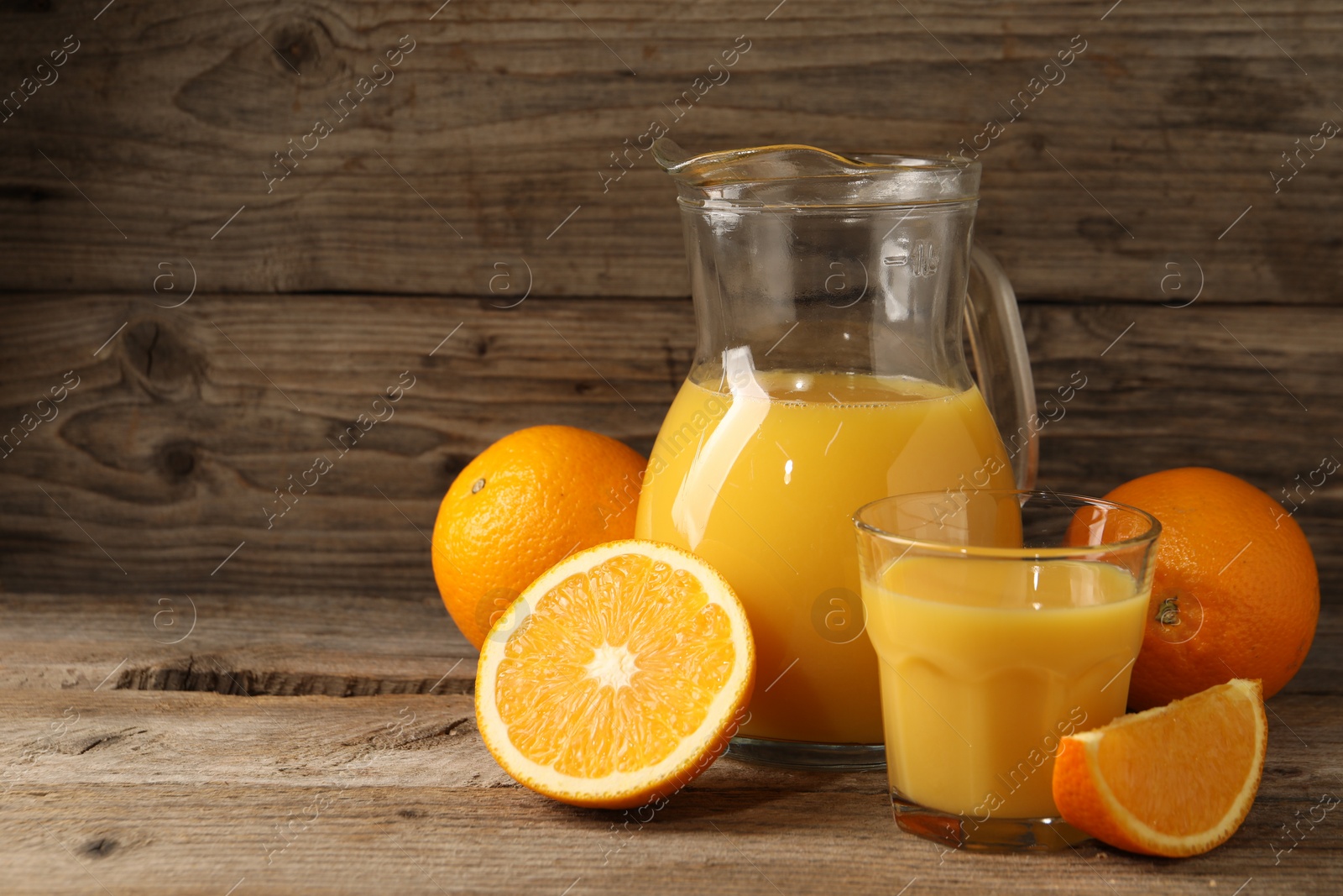 Photo of Tasty fresh oranges and juice on wooden table, space for text