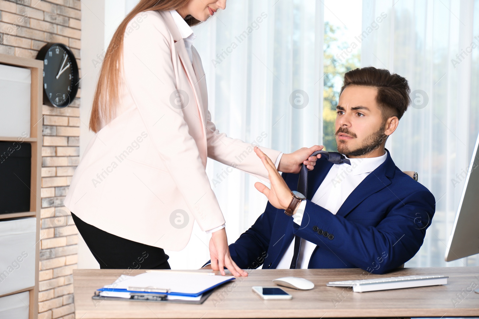 Photo of Woman molesting her male colleague in office. Sexual harassment at work