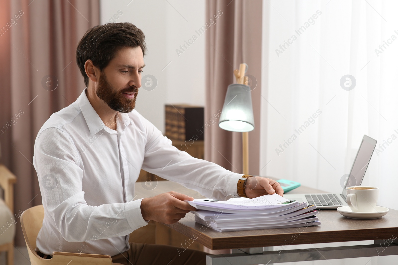 Photo of Happy businessman working with documents at wooden table in office