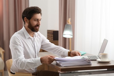 Happy businessman working with documents at wooden table in office