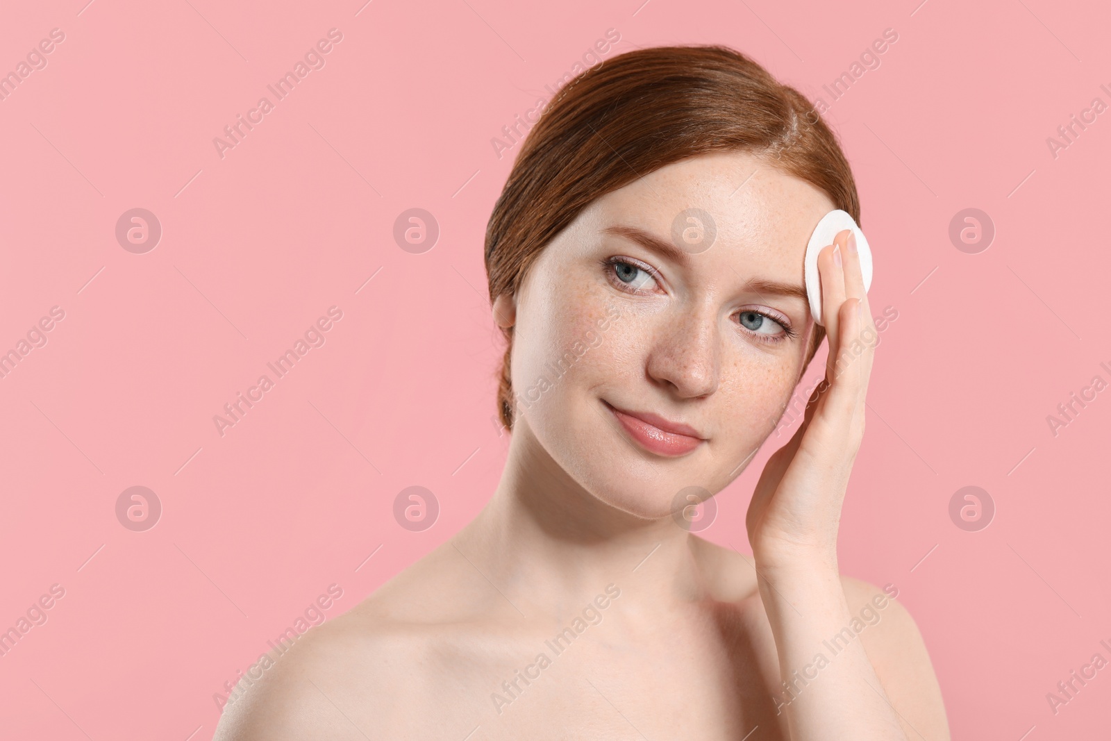 Photo of Beautiful woman with freckles wiping face on pink background