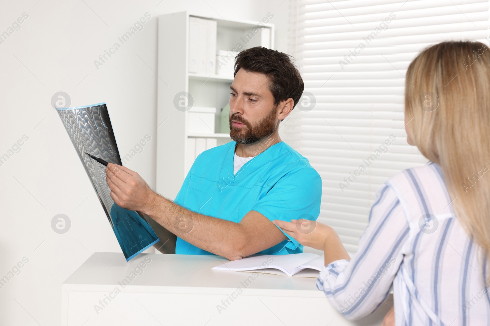 Photo of Doctor with neck MRI scan consulting patient in hospital