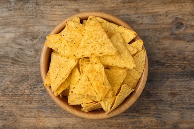 Bowl with tasty Mexican nachos chips on wooden table, top view