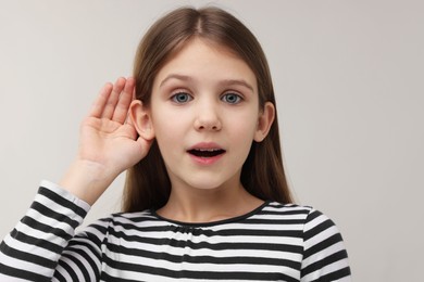 Little girl with hearing problem on grey background