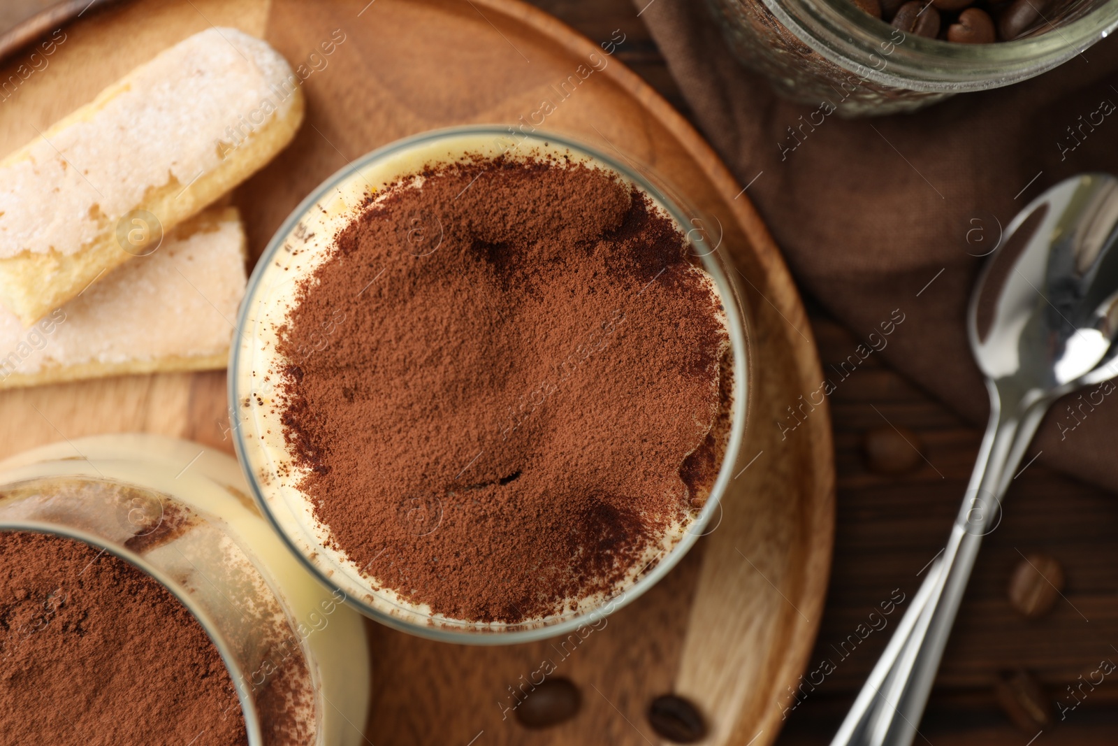 Photo of Delicious tiramisu in glasses served on wooden table, flat lay