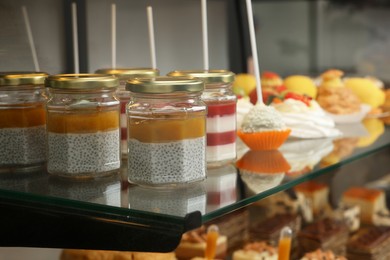 Showcase with different tasty desserts in store, closeup. Space for text