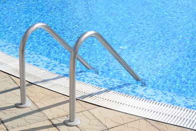 Photo of Outdoor swimming pool with ladder and handrails on sunny day