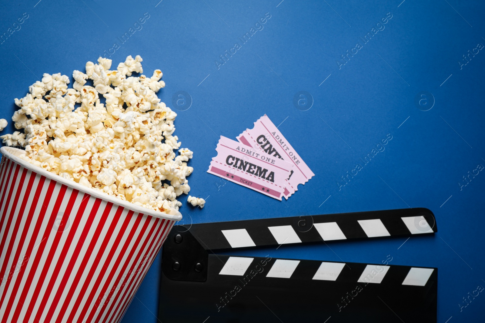 Photo of Flat lay composition with delicious popcorn and cinema items on blue background