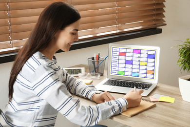 Photo of Young woman planning her schedule with calendar app on laptop in office