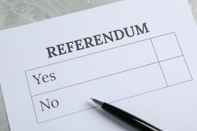 Referendum ballot with pen on grey table, closeup