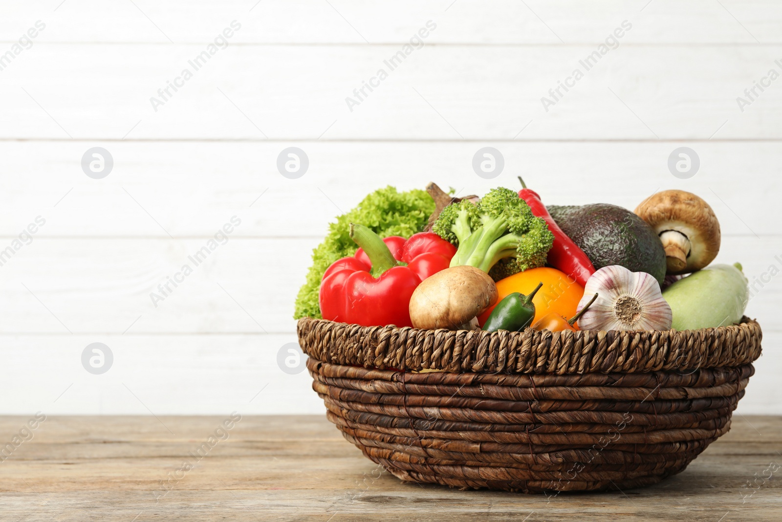 Photo of Fresh vegetables in wicker bowl on wooden table