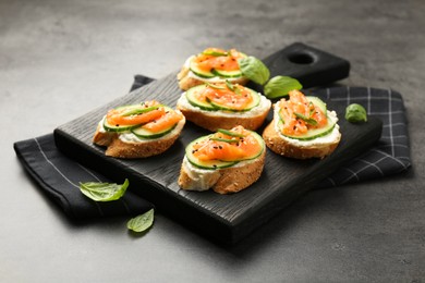 Photo of Tasty canapes with salmon, cucumber and cream cheese on grey table