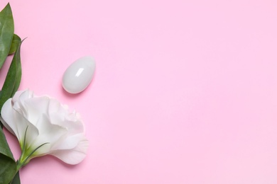 Photo of Beautiful flower and jade egg on pink background, flat lay with space for text