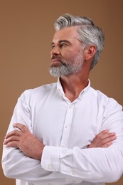 Portrait of confident man with beautiful hairstyle on light brown background