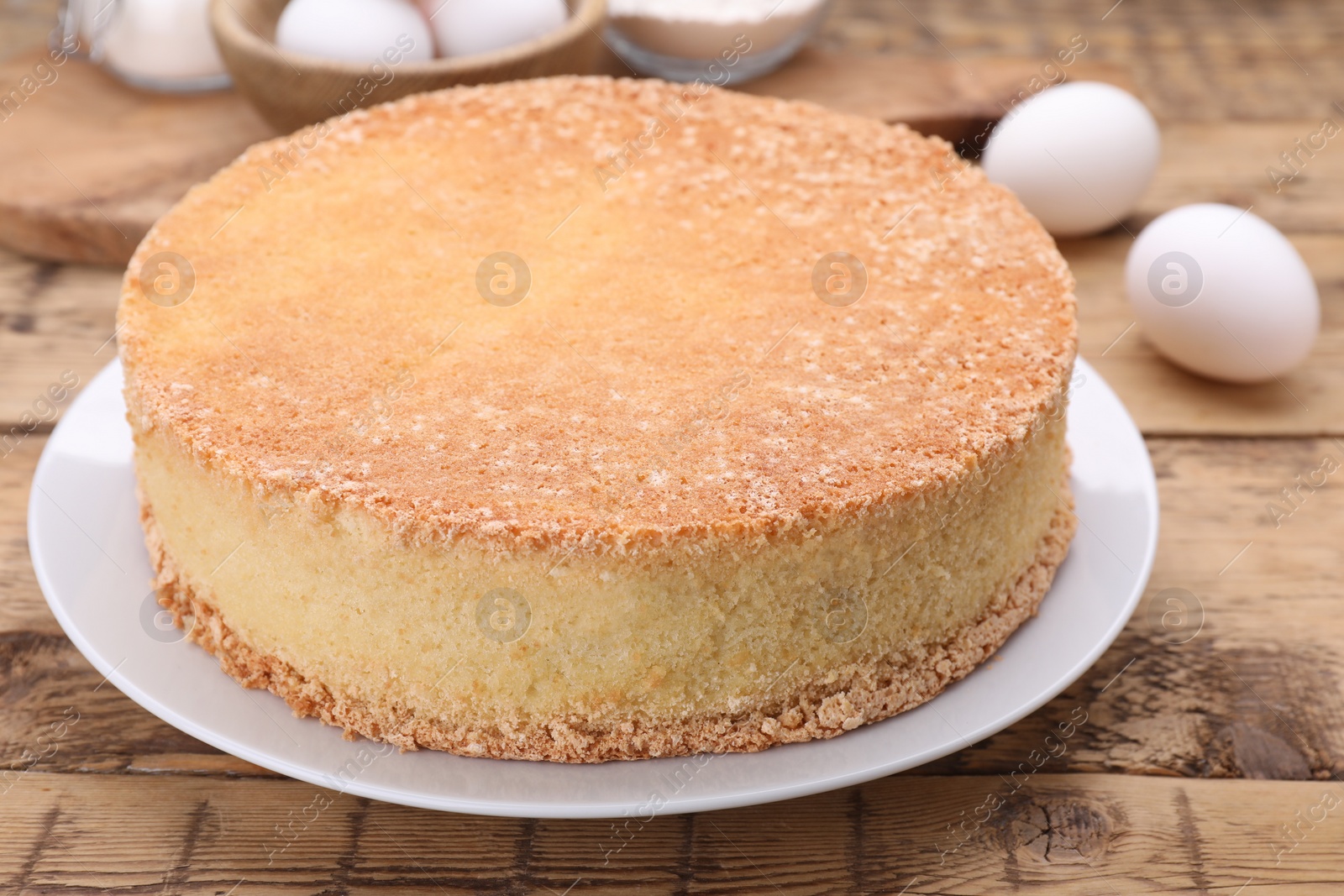 Photo of Plate with delicious sponge cake on wooden table, closeup