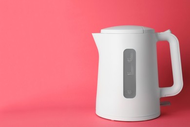Photo of New modern electric kettle on red background, space for text