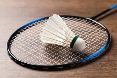 Photo of Feather badminton shuttlecock and racket on wooden table, closeup