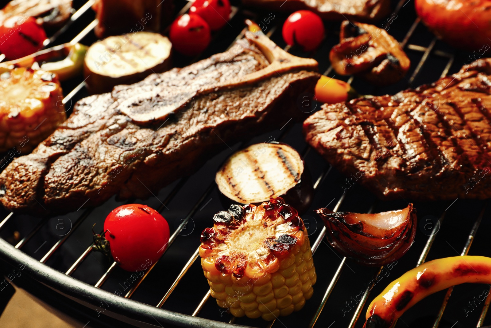 Photo of Fresh grilled meat steaks and vegetables on barbecue grate, closeup