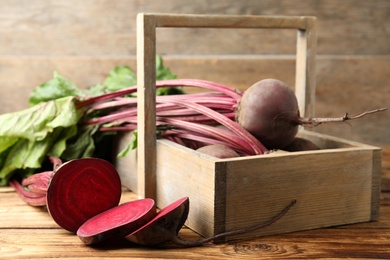 Cut and whole raw beets on wooden table