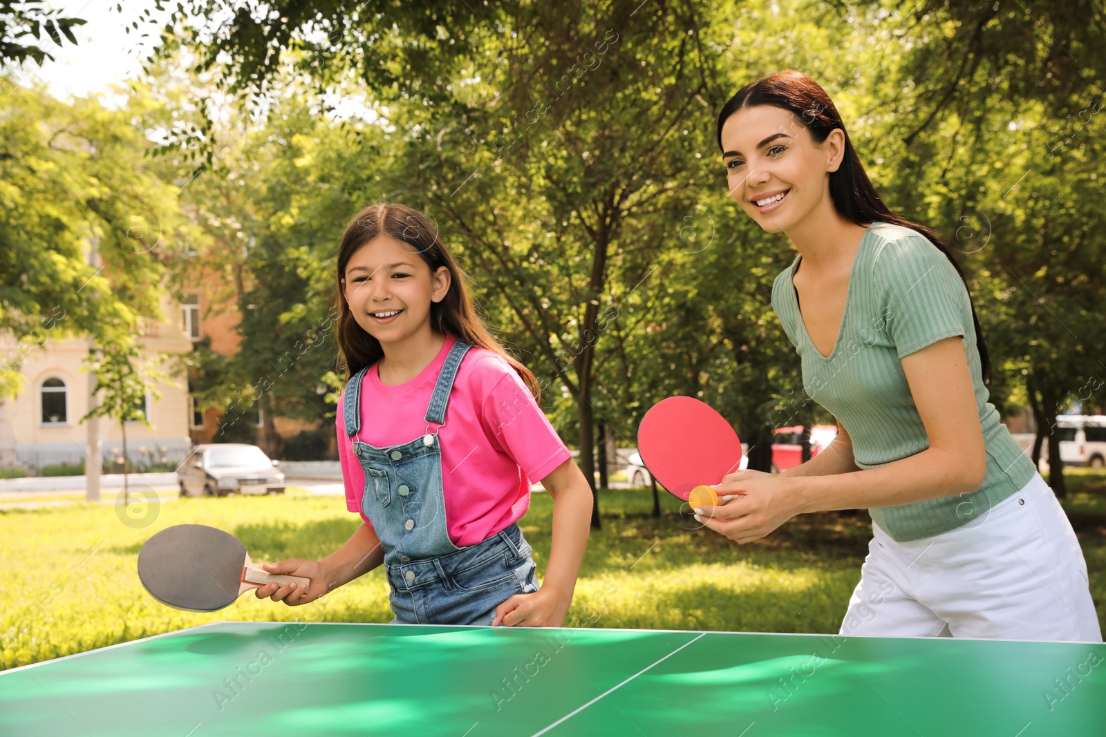 Photo of Young woman with her daughter playing ping pong in park