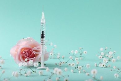 Photo of Cosmetology. Medical syringe, rose and gypsophila flowers on turquoise background, space for text