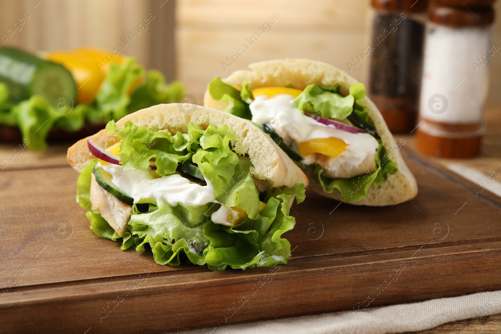 Photo of Delicious pita sandwiches with chicken breast and vegetables on wooden table, closeup