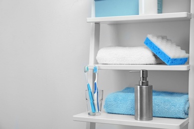 Towels, toiletries and soap dispenser on shelves in bathroom. Space for text