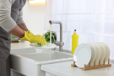 Photo of Man washing plate above sink in kitchen, closeup