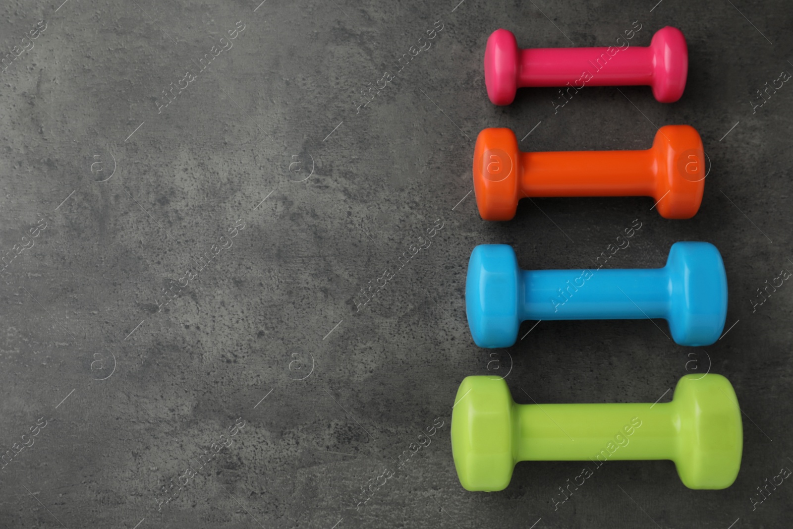 Photo of Different dumbbells on grey table, flat lay. Space for text