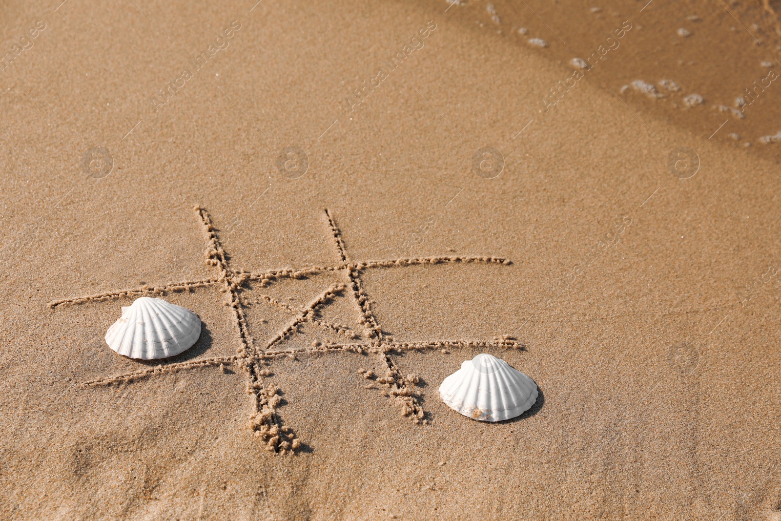 Photo of Playing Tic tac toe game with shells on sand near sea. Space for text