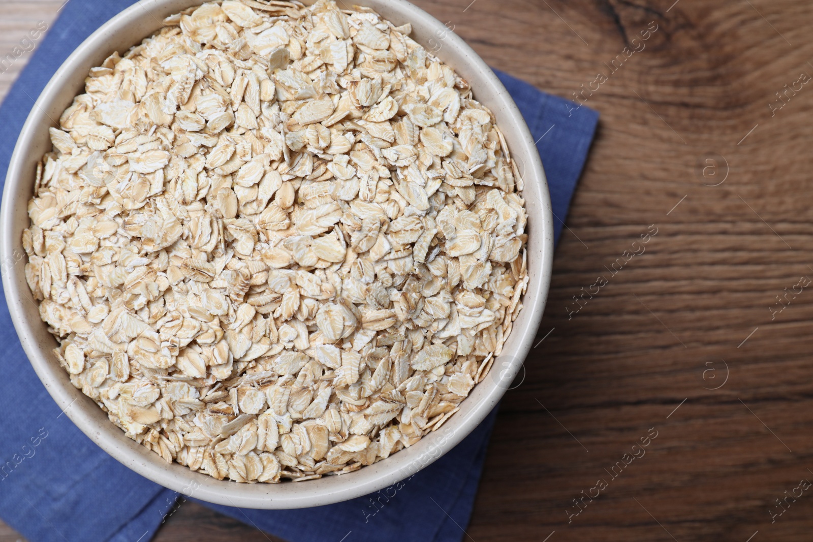 Photo of Bowl with oatmeal on wooden table, top view. Space for text