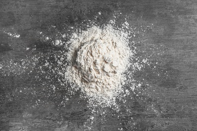 Heap of wheat flour on gray background, top view