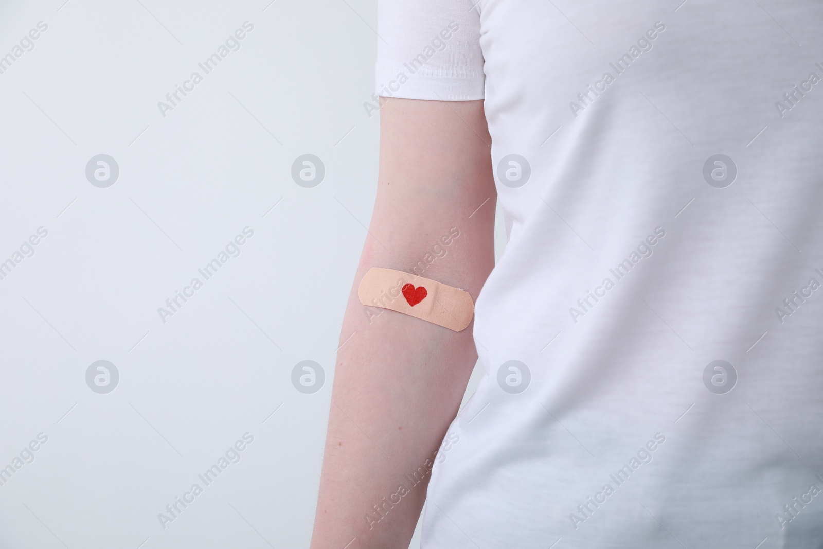 Photo of Blood donation concept. Woman with adhesive plaster on arm against white background, closeup. Space for text