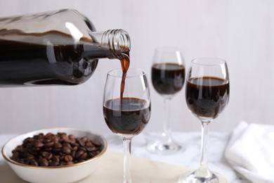 Photo of Pouring coffee liqueur from bottle into glass at table