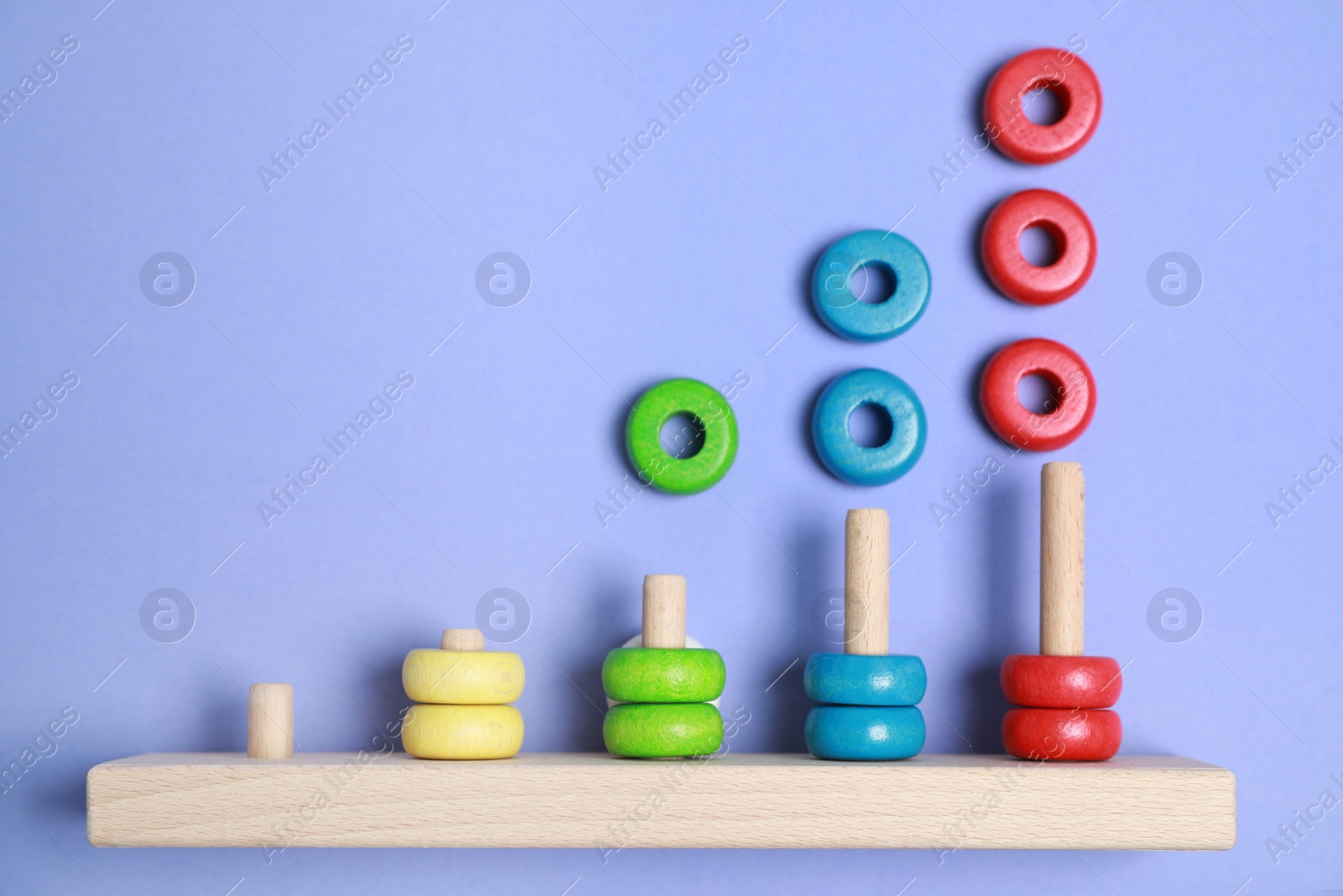 Photo of Stacking and counting game wooden pieces on violet background, top view. Educational toy for motor skills development