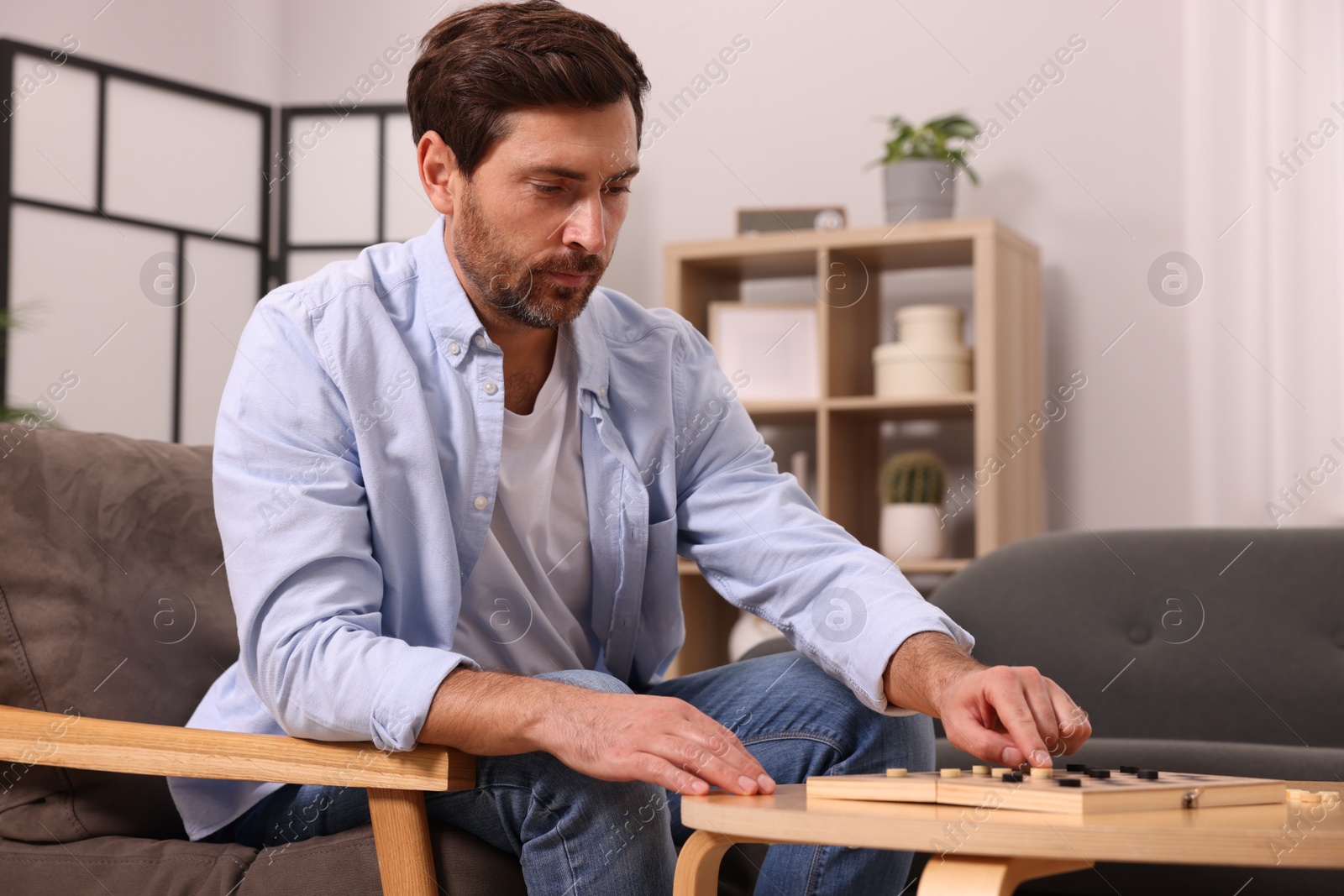 Photo of Man playing checkers in armchair at home