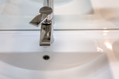 Photo of Chrome tap and white sink in bathroom