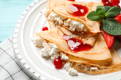 Photo of Delicious thin pancakes with cottage cheese and jam on plate, closeup