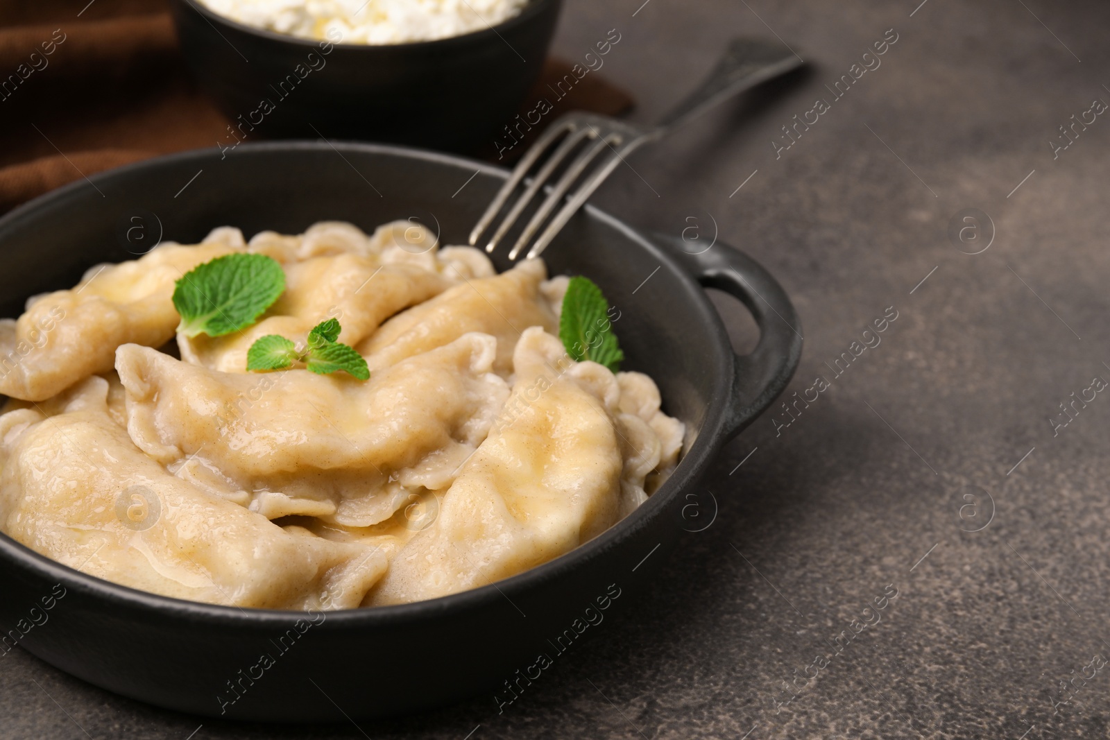 Photo of Delicious dumplings (varenyky) with cottage cheese and mint served on brown table