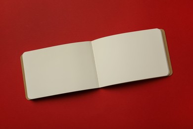 Photo of Stylish open notebook with blank sheets on red background, top view