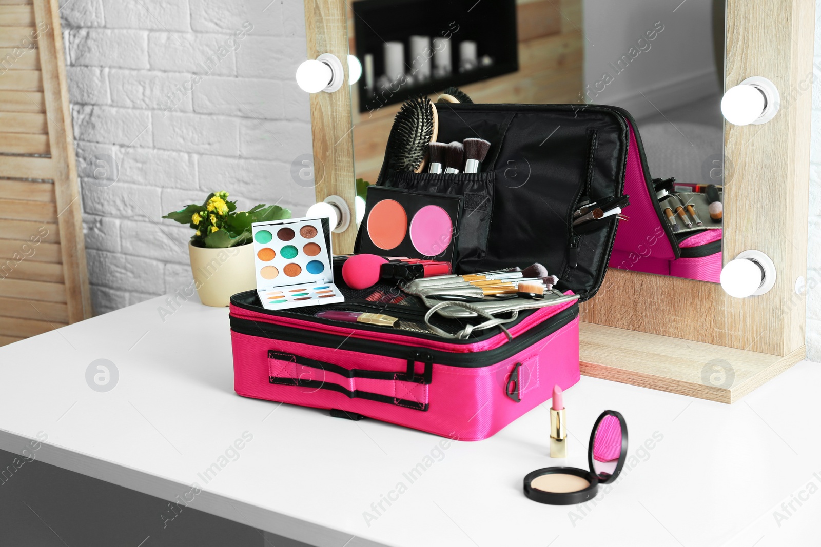 Photo of Beautician case with professional makeup products and tools on dressing table