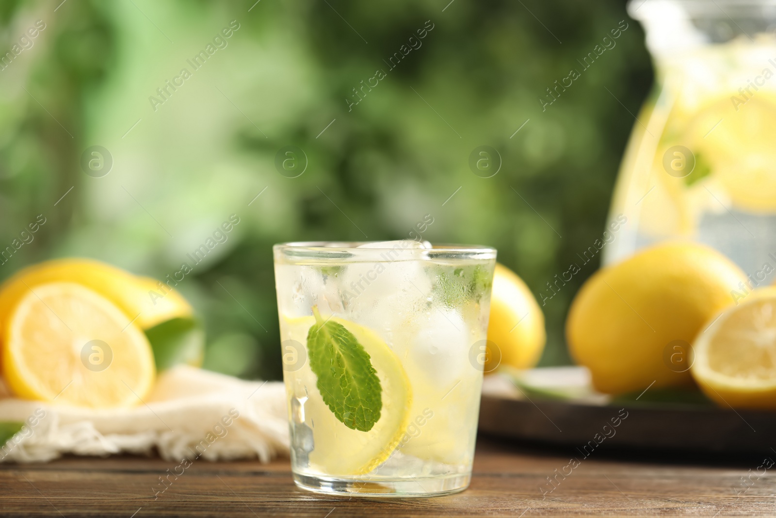 Photo of Cool freshly made lemonade and fruits on wooden table