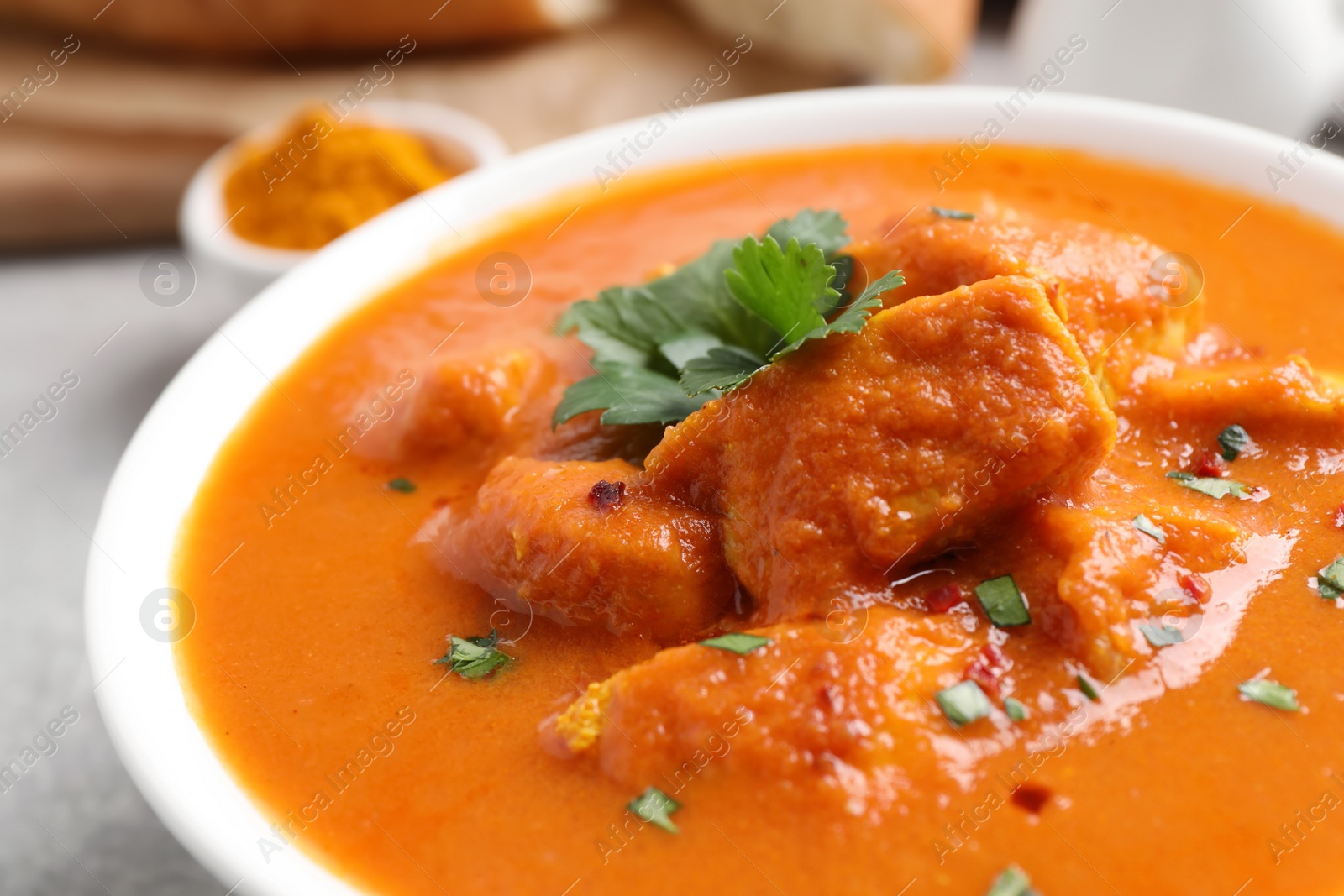 Photo of Bowl of delicious chicken curry on light grey table, closeup