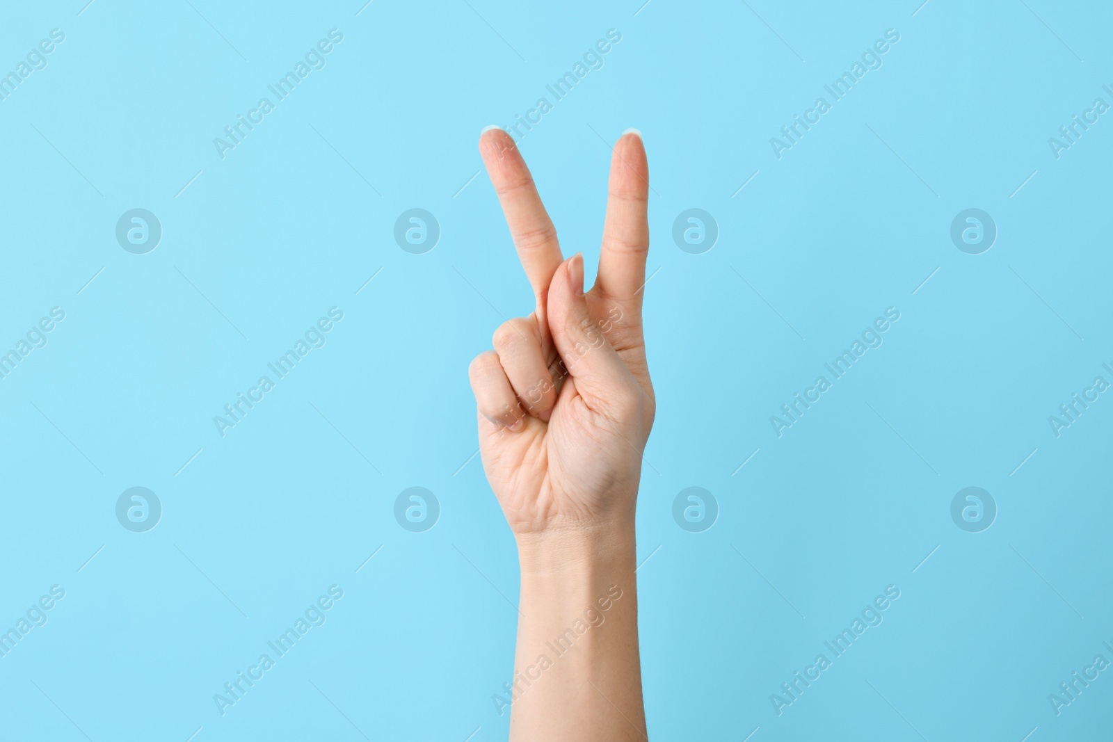 Photo of Woman showing K letter on color background, closeup. Sign language