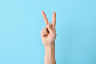 Photo of Woman showing K letter on color background, closeup. Sign language