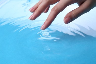 Woman touching clear water, closeup. Making ripples